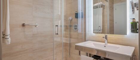 A modern bathroom with a glass-enclosed shower, a white sink, and a large mirror.