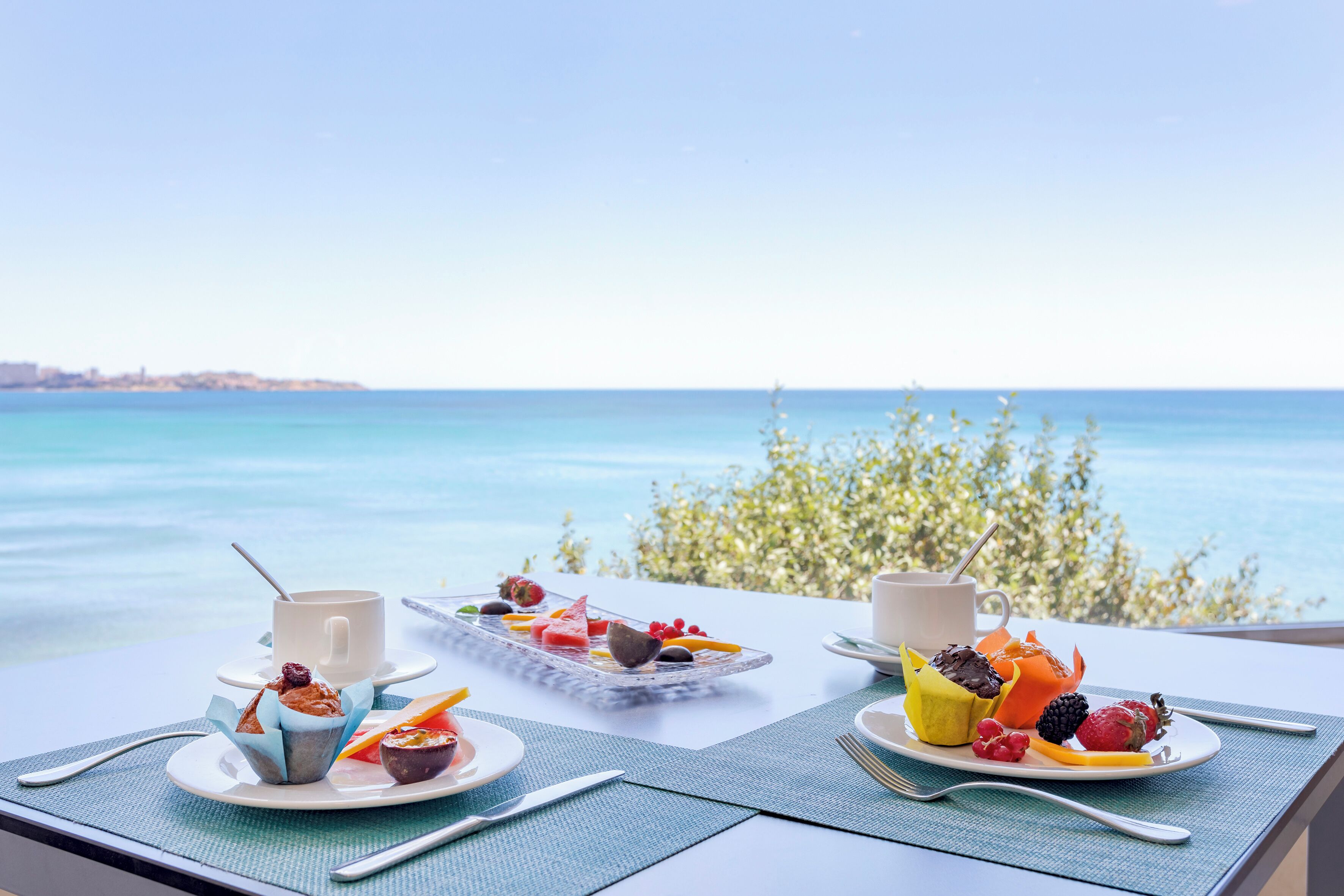 A table with breakfast items and a view of the sea.