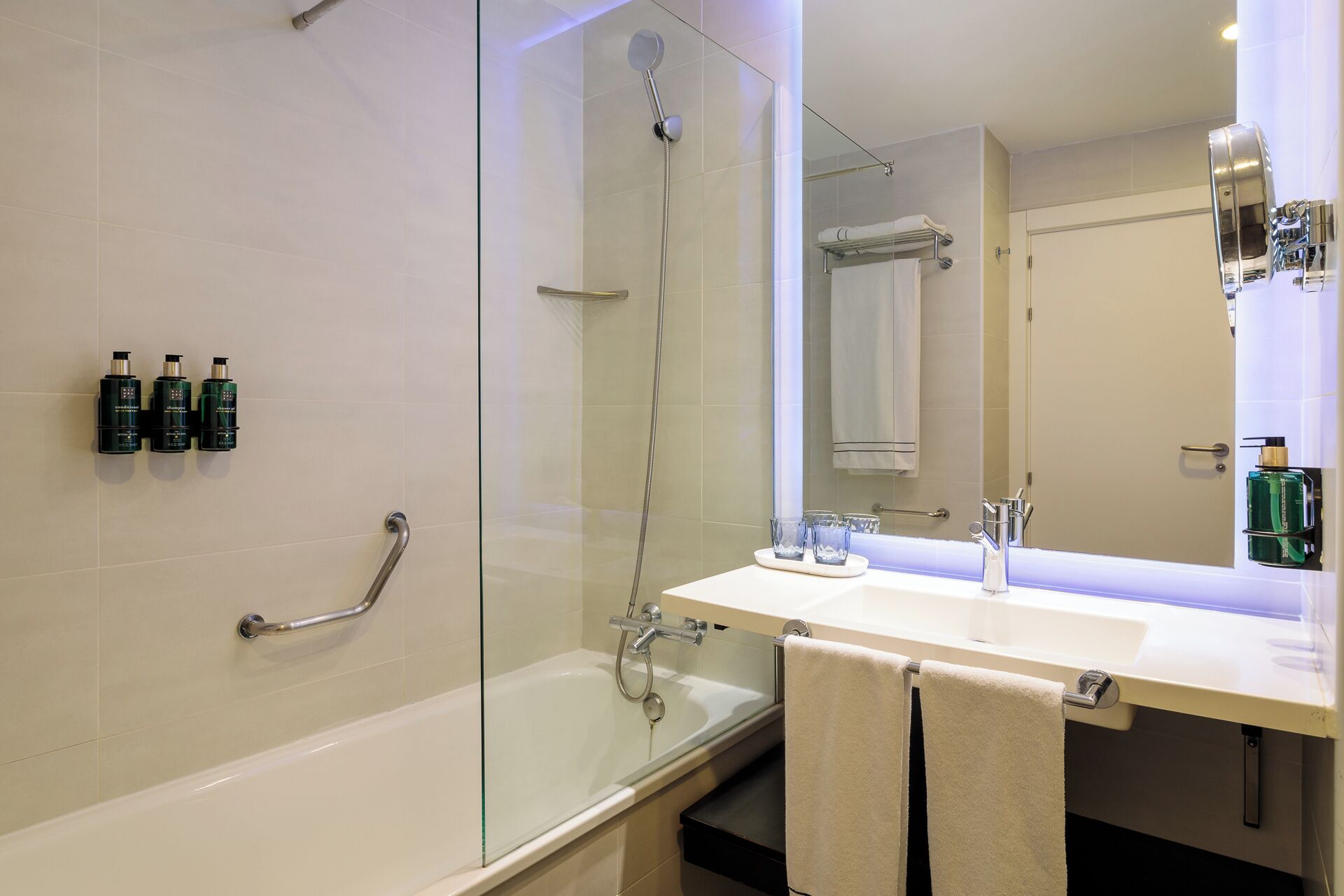 Ein modernes Badezimmer mit Duschkabine aus Glas, einer Badewanne, einem Waschtisch mit Spiegel und zwei Handtüchern.