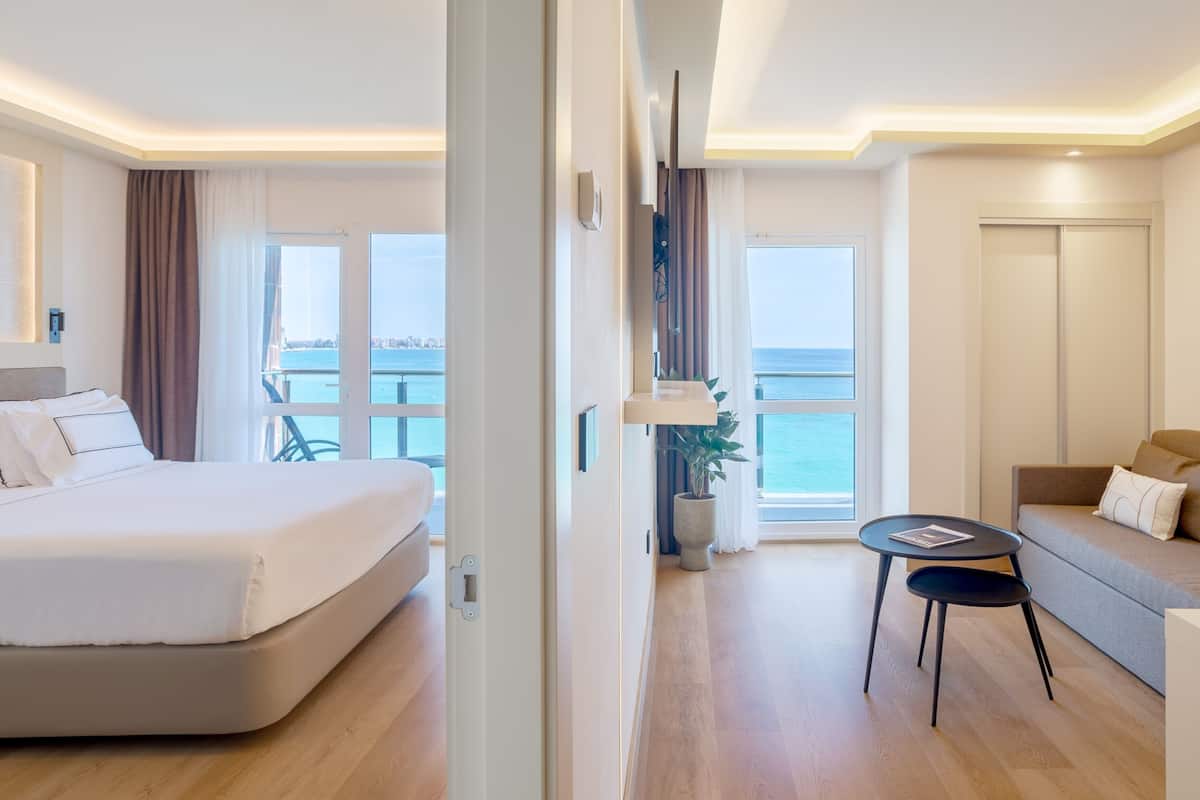 Un hotel moderno con cama, sofá, una mesita y vistas al mar.