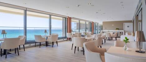 A spacious dining area with high ceilings and large windows overlooking the ocean.