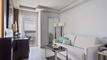 Une chambre d’hôtel moderne dotée d’un balcon, d’un canapé, d’une table basse et d’un bureau avec une lampe.