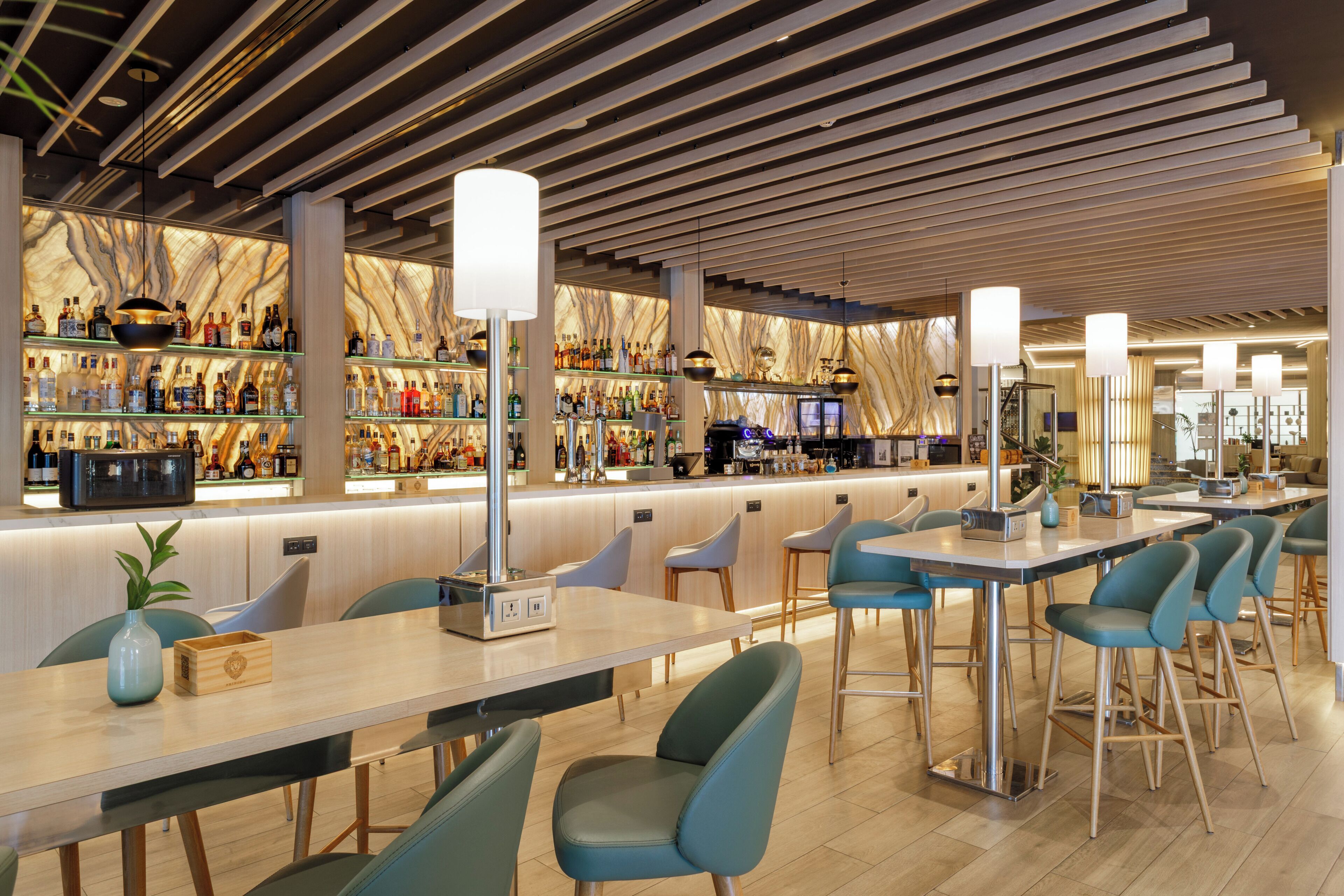 Un área de bar moderna con diversas opciones de asientos y una variedad de botellas de licores a la vista.