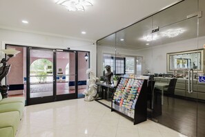 A reception area with a glass door entrance, a reception desk, a magazine rack, and a view of the outside. - SureStay by Best Western Morgan Hill (Morgan Hill)