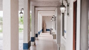 Un pasillo con columnas, una estatua y luces en la pared.