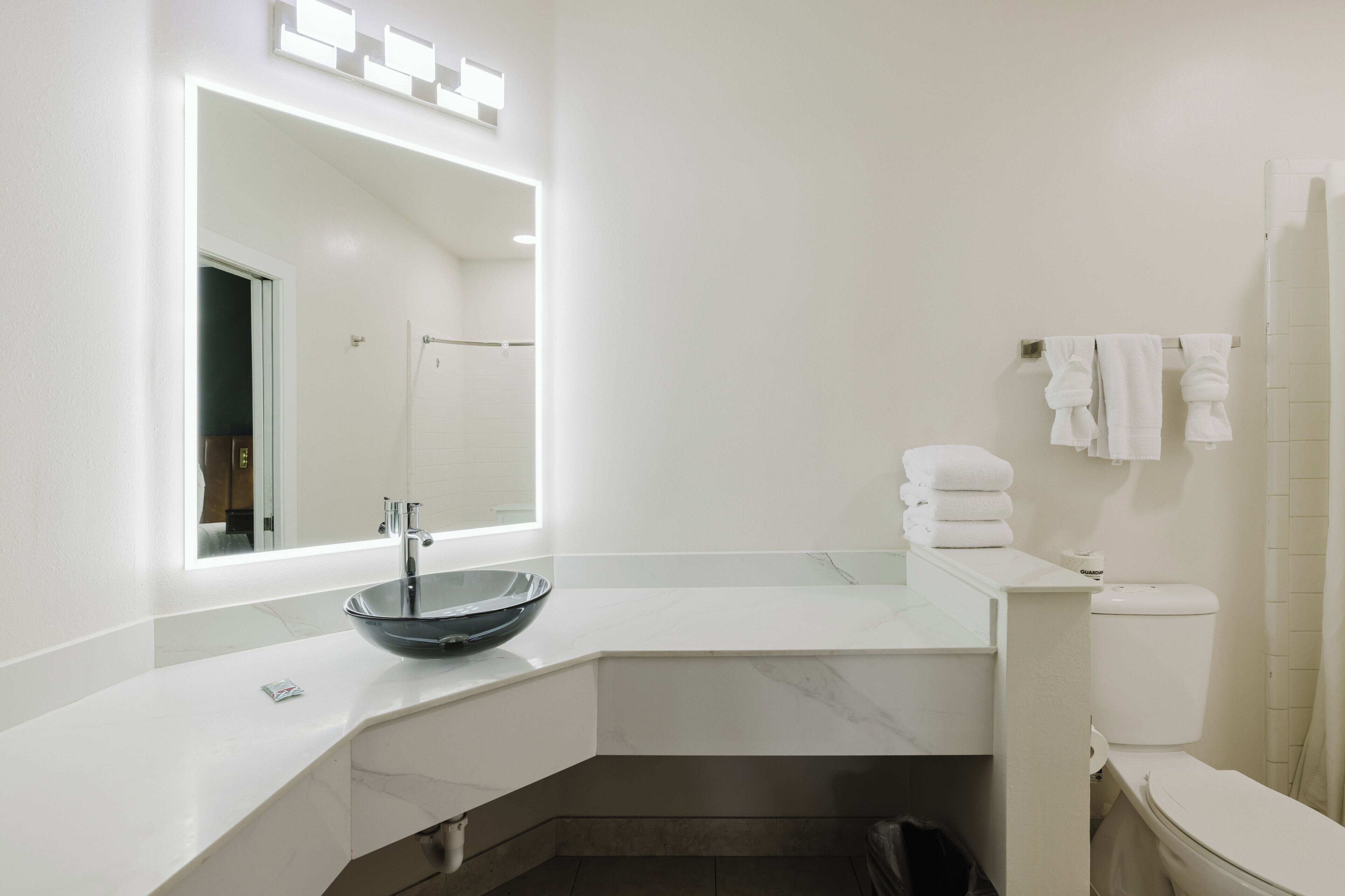 Un baño moderno con un espejo grande, un lavabo sobre encimera, un inodoro y un perchero para toallas.