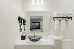 A bathroom with a glass sink, a mirror, a towel rack, and a toilet. - SureStay by Best Western Morgan Hill (Morgan Hill)