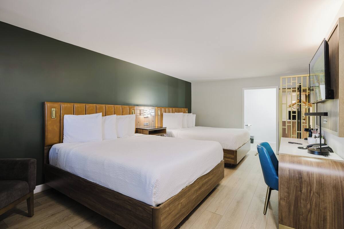 A hotel room with a large bed, a desk, a chair, and a television.