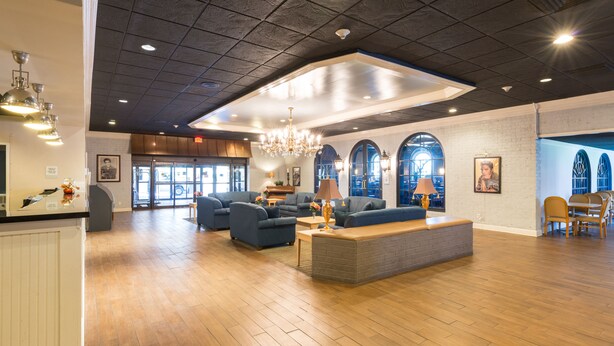 A spacious lobby with a high ceiling, wooden flooring, and a central seating area with sofas and a coffee table. - Travelodge by Wyndham Memphis Airport/Graceland (Memphis)