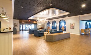 A spacious lobby with a high ceiling, wooden flooring, and a central seating area with sofas and a coffee table. - Travelodge by Wyndham Memphis Airport/Graceland (Memphis)