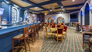 A restaurant with a bar area, wooden chairs, tables, and a patterned carpet. - Travelodge by Wyndham Memphis Airport/Graceland (Memphis)