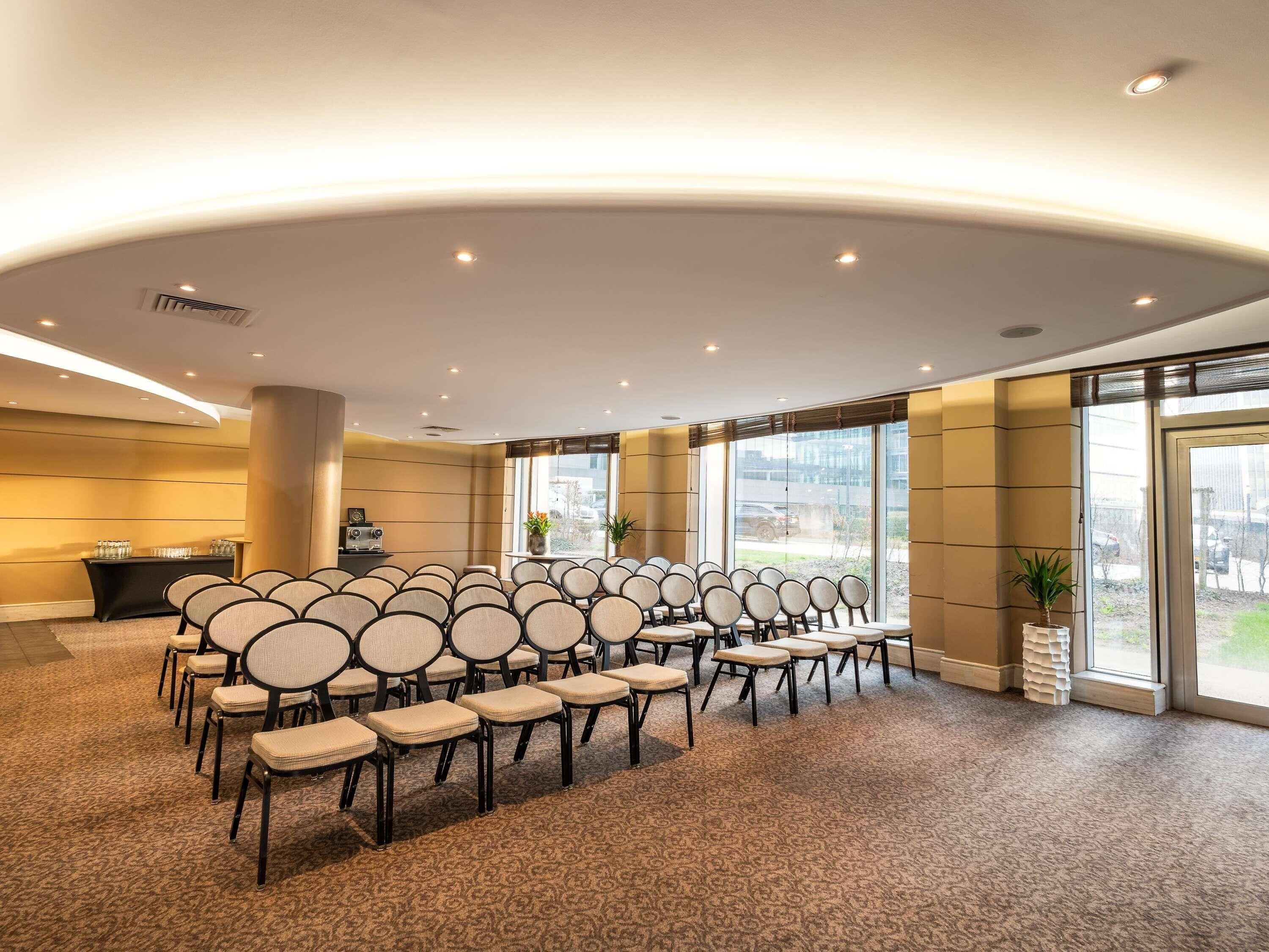 A conference room with rows of chairs, a reception desk, and large windows.