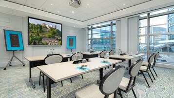 A conference room with large windows, a projector, and presentation screens.