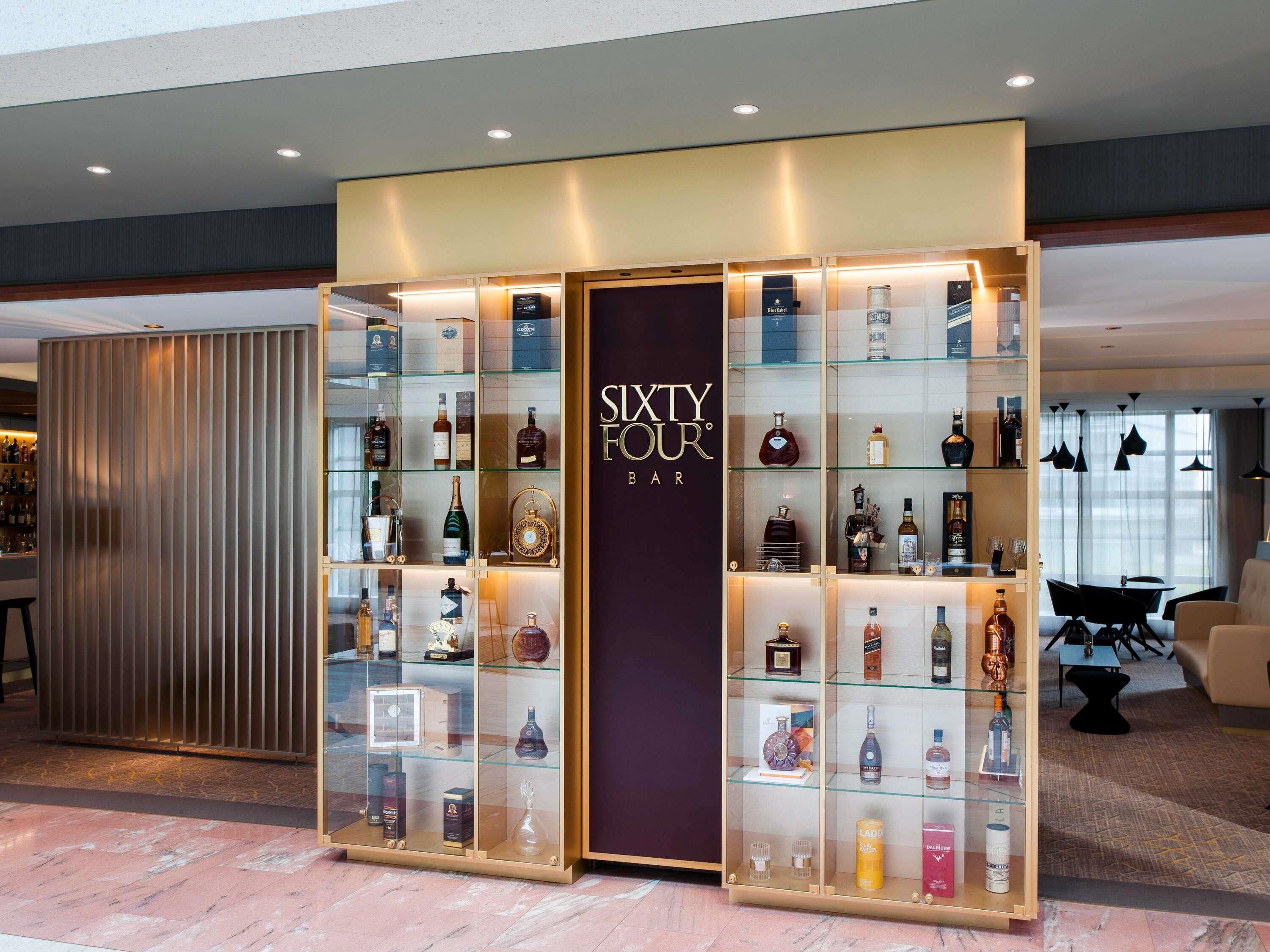 A bar area with glass display cases of liquor bottles and a sign reading 'Sixty Four Bar'.