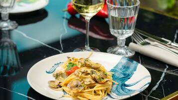 A plate of pasta with clams and a glass of white wine on a table.