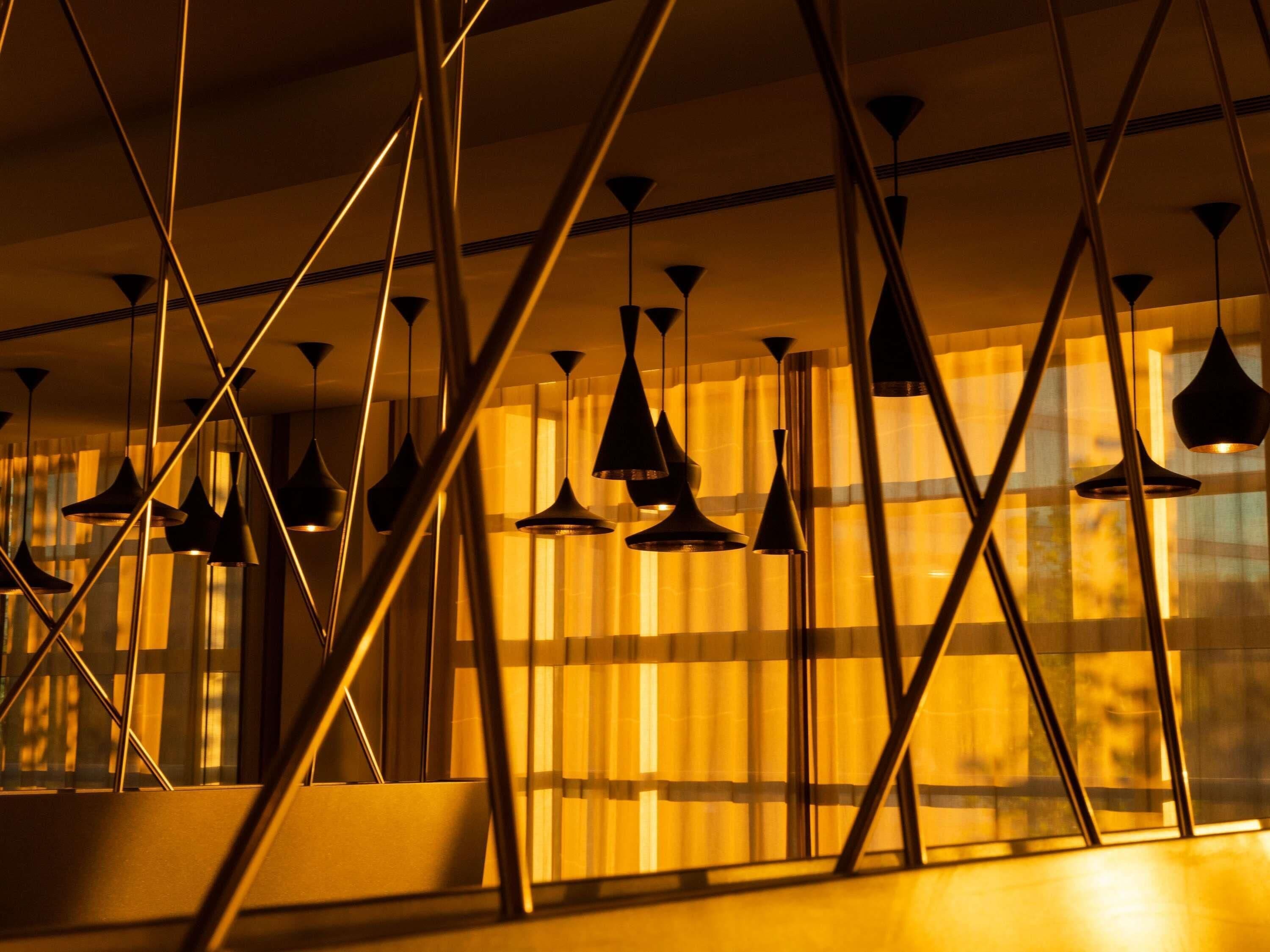 Ein modernes Interieur mit geometrischen Deckenstrukturen und Pendelleuchten.