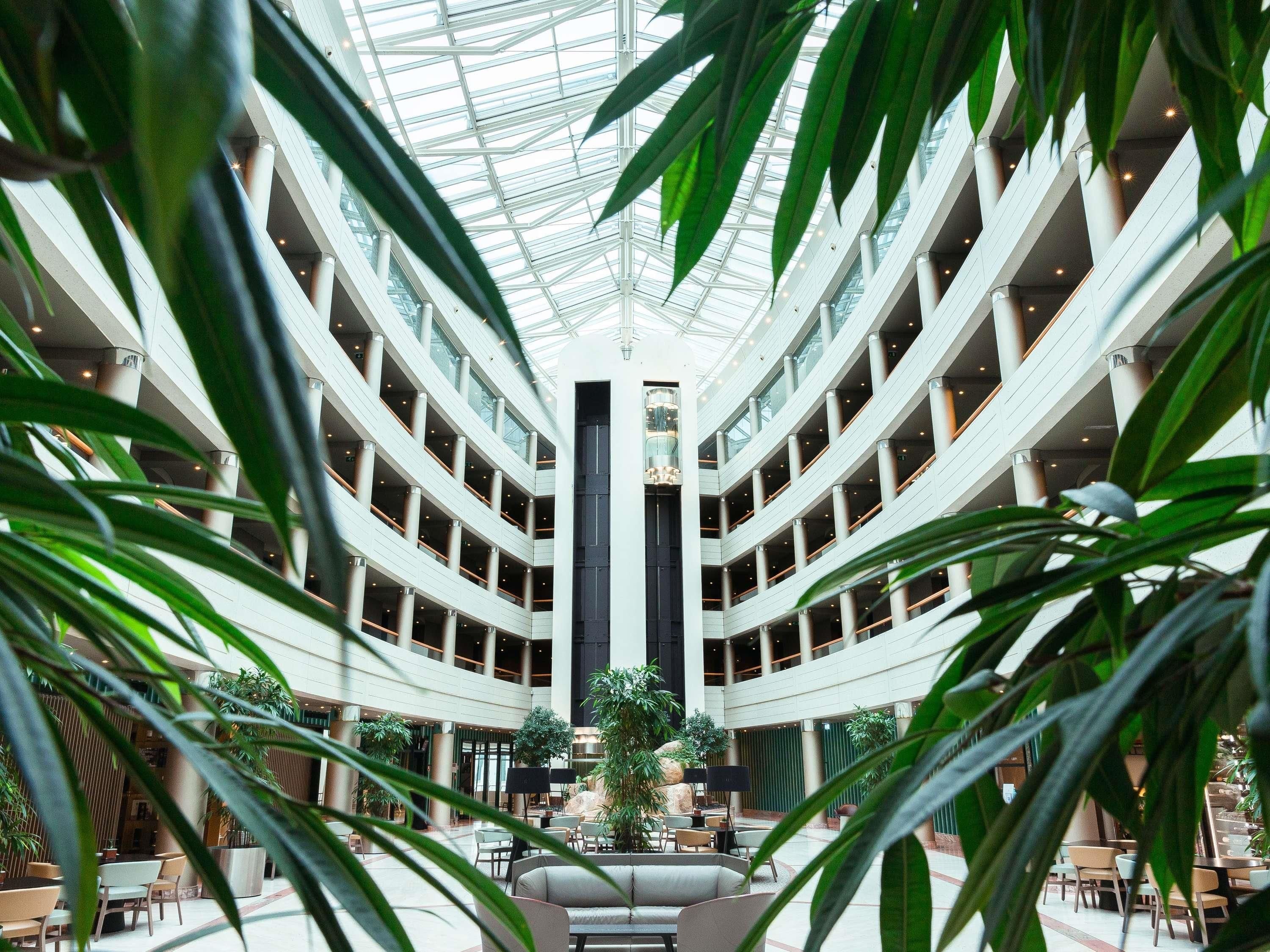 A multi-level atrium with a central column, surrounded by seating areas and plants.