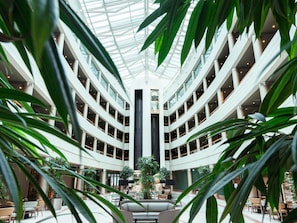 Un atrium à plusieurs niveaux, doté d’une colonne centrale, et entouré d’espaces aménagés pour s’asseoir et de plantes.