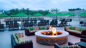 A circular outdoor seating area with a fire pit, surrounded by lounge chairs and sofas.