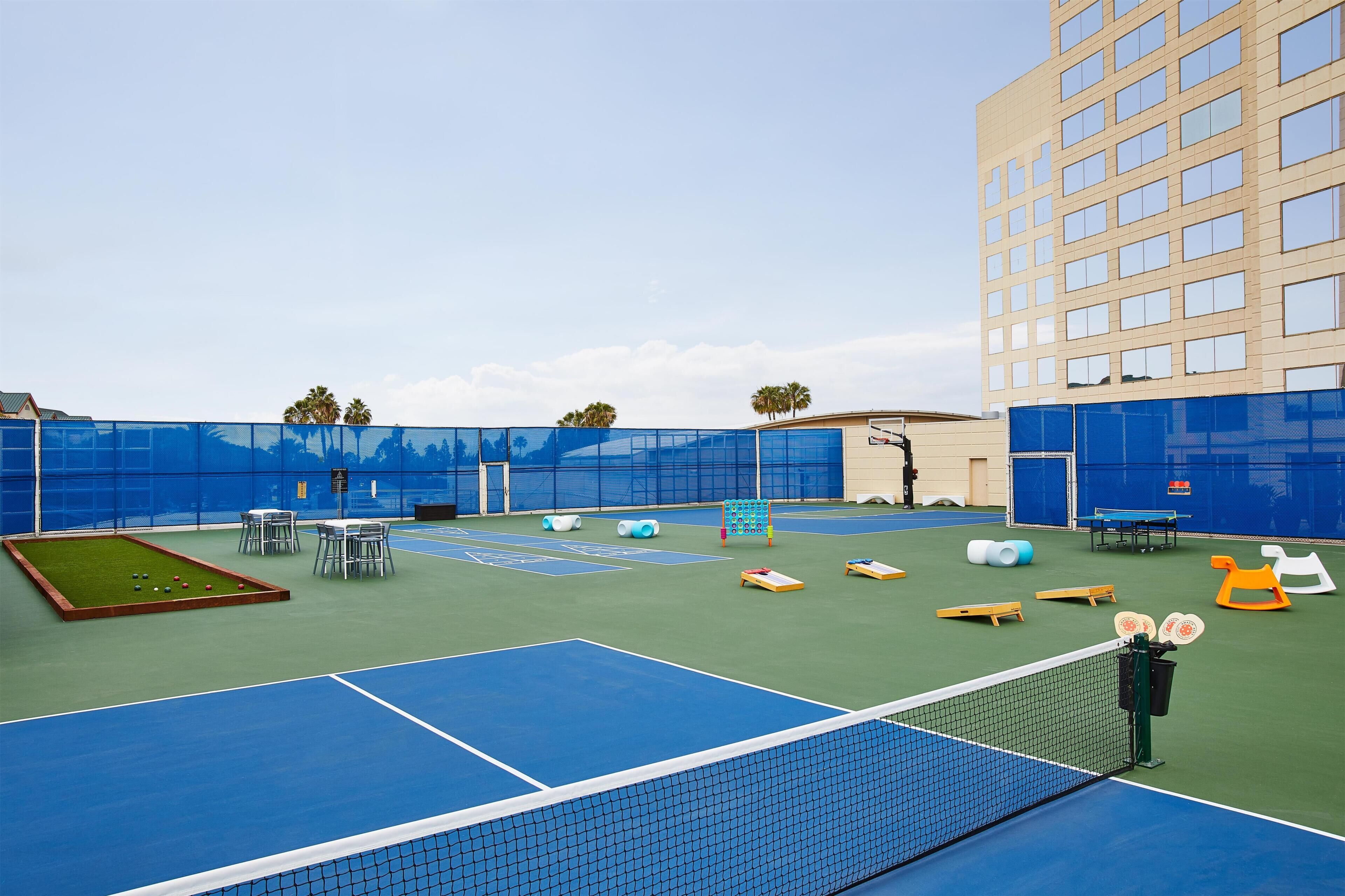Un recinto deportivo interior con cancha de tenis, mesa de billar y zonas de estar.
