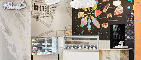 An ice cream shop with a marble counter, a display case with ice cream, and a wall with ice cream illustrations and text.