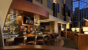 A modern bar area with a curved counter, multiple seating options, and a large screen above the bar.
