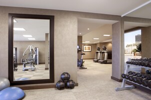 Un gimnasio con equipo de ejercicio, un espejo y un estante con mancuernas.