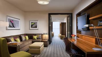 Une chambre d’hôtel équipée d’un canapé, d’un fauteuil, d’un bureau et d’une télévision.