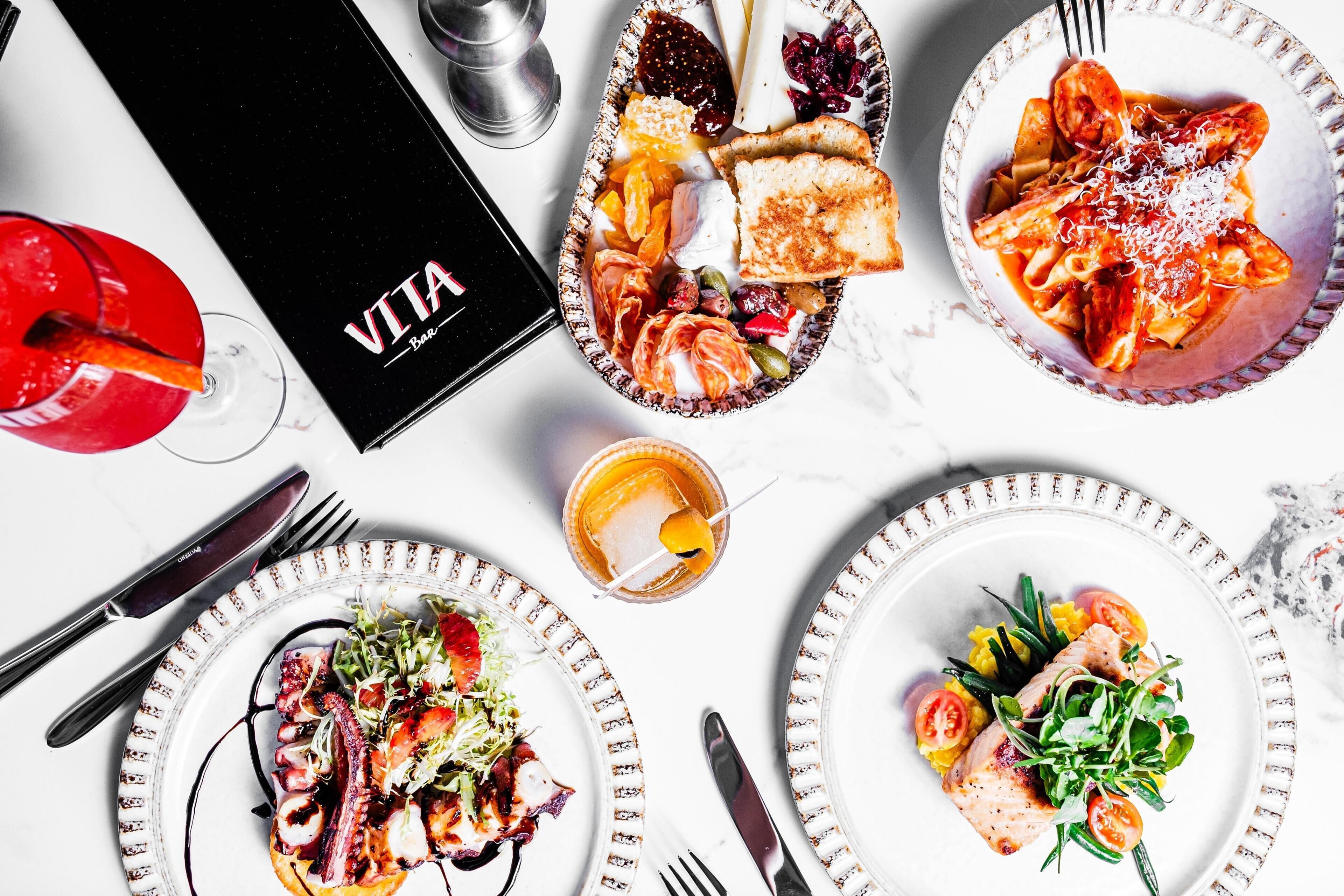 Una mesa con diversos platos, una bebida y un menú.