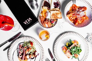 Una mesa con diversos platos, una bebida y un menú.