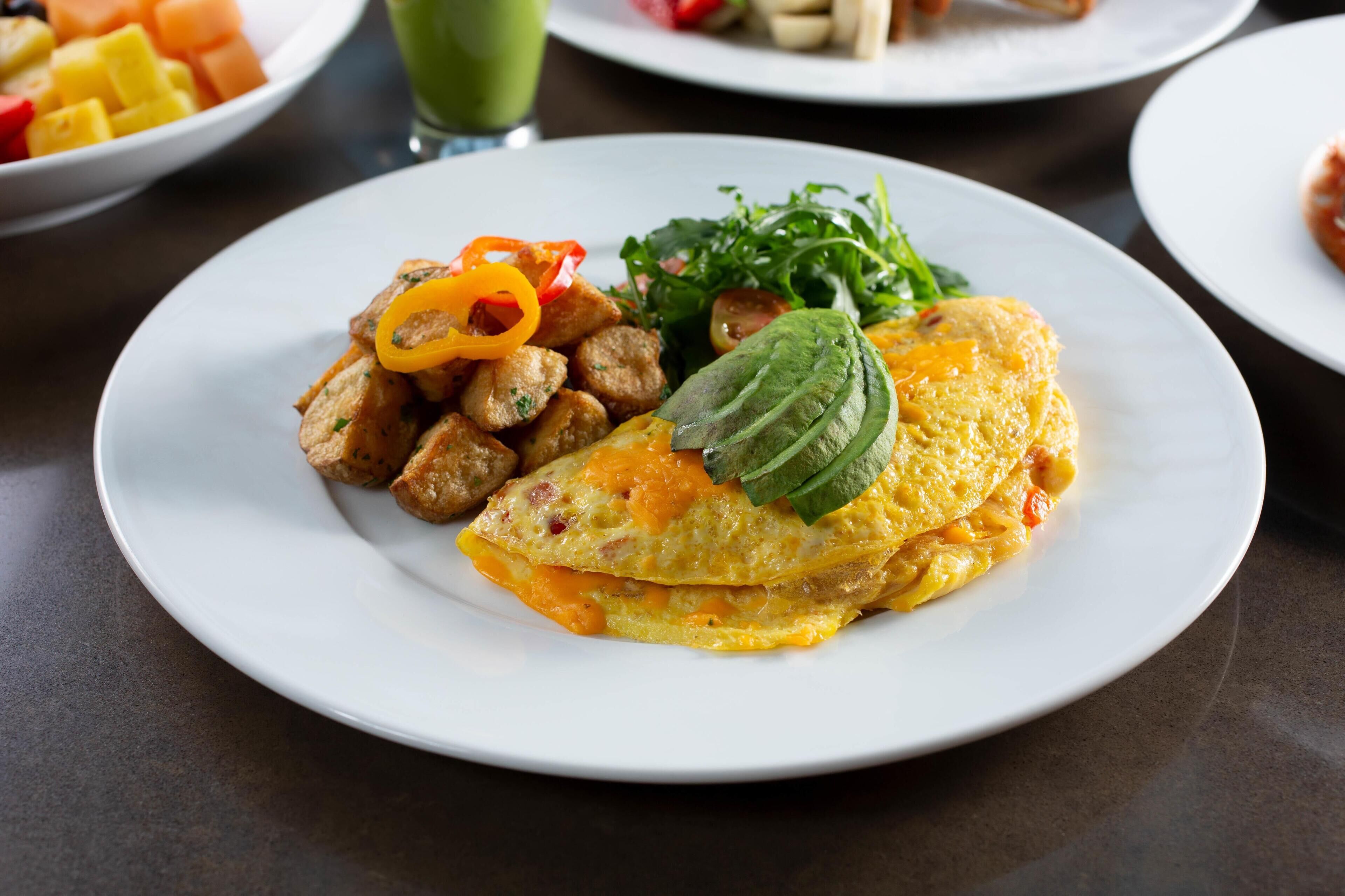 A plate with an omelette, vegetables, and a side dish.