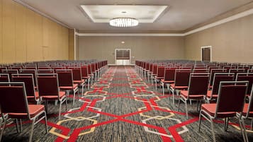 A conference room with rows of chairs, a patterned carpet, and a ceiling light fixture.