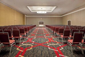A conference room with rows of chairs, a patterned carpet, and a ceiling light fixture. - Four Points By Sheraton Peoria (Peoria)