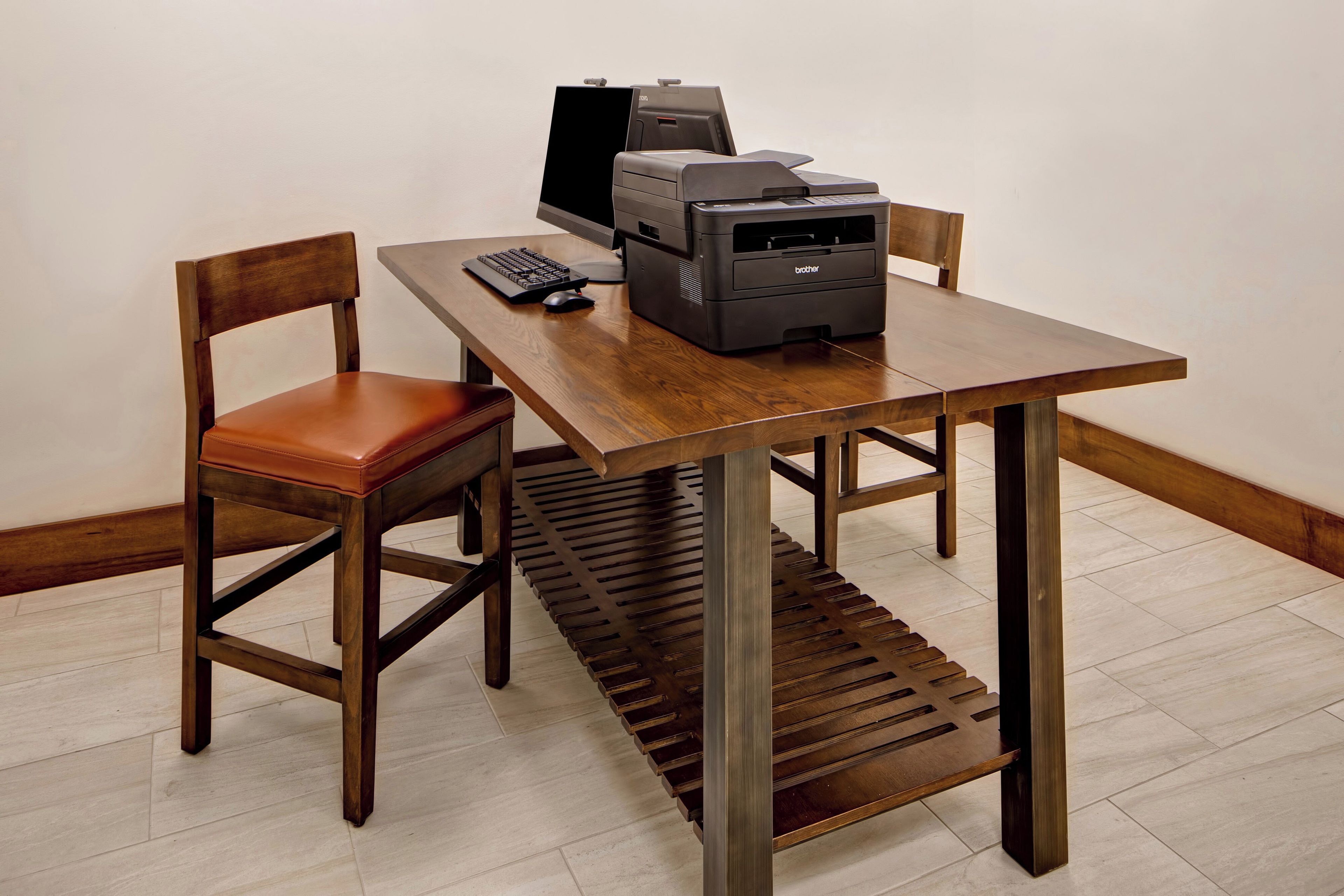 Una mesa de madera con una computadora, teclado e impresora.