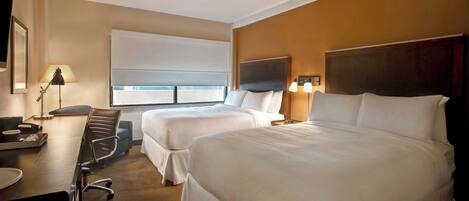 A hotel room with two beds, a desk, a chair, a TV, and a window with a view.