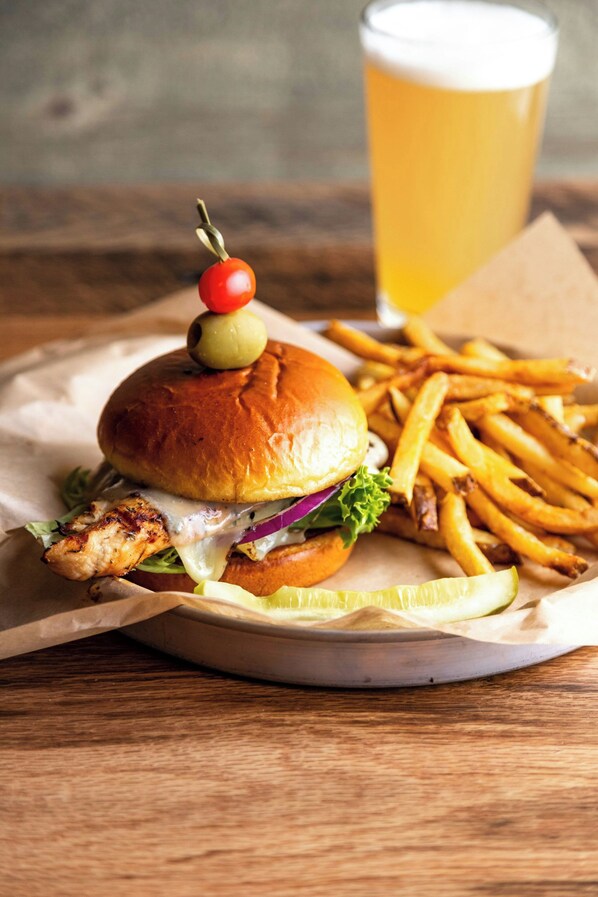 Una hamburguesa con papas fritas y un vaso de cerveza sobre una mesa de madera.