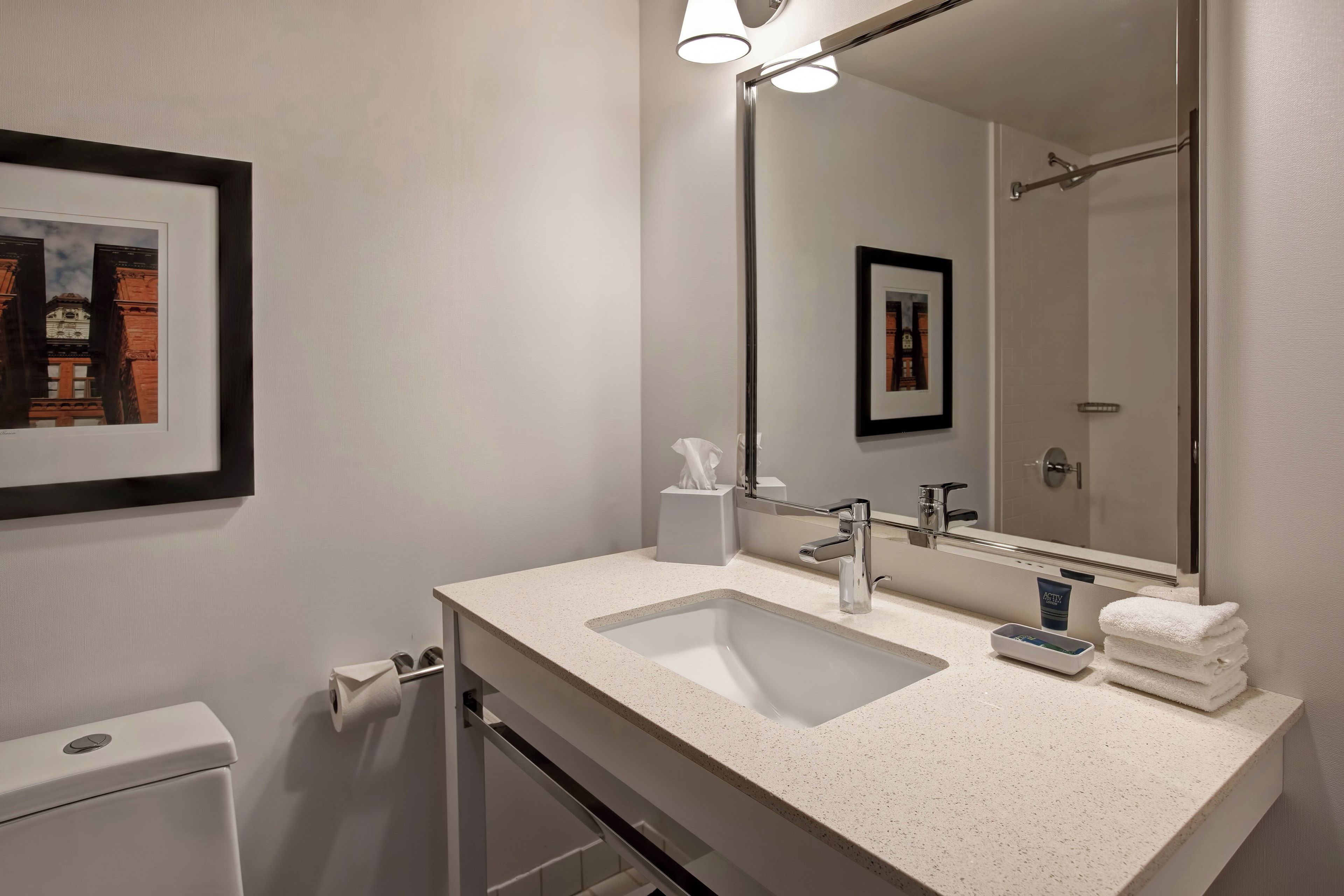 A modern bathroom with a large mirror, two sinks, and a toilet.