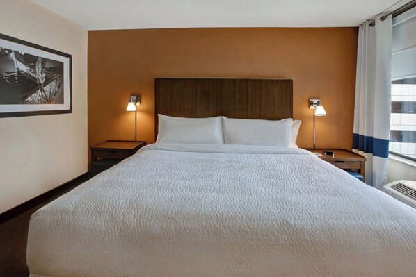 A hotel room with a large bed, two bedside tables, a headboard, and a wall-mounted picture.