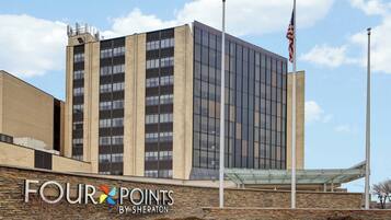 A modern building with a glass facade, a stone wall with signage, and an American flag.