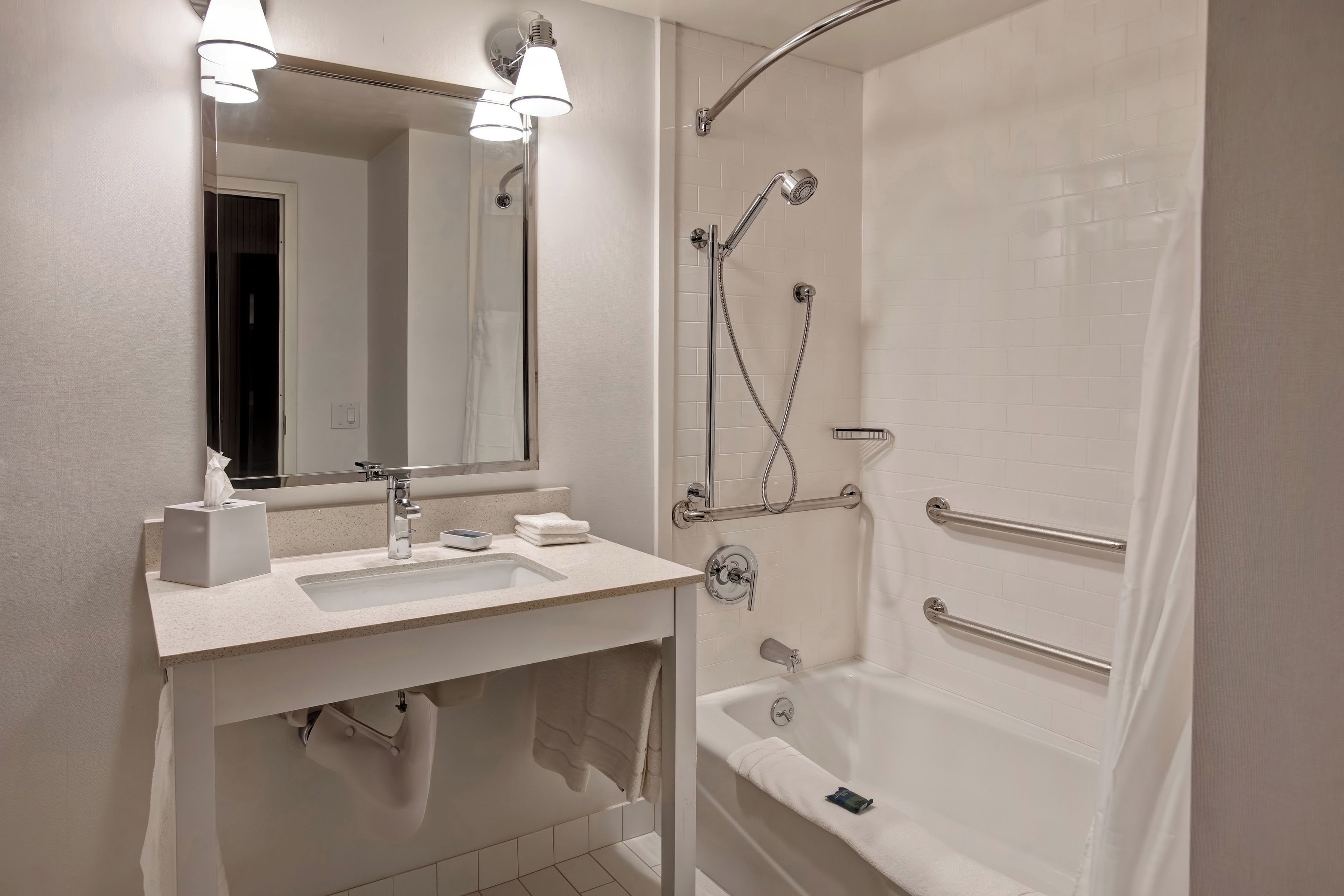 A modern bathroom with a sink, mirror, towel rack, and a walk-in shower with a handheld showerhead.