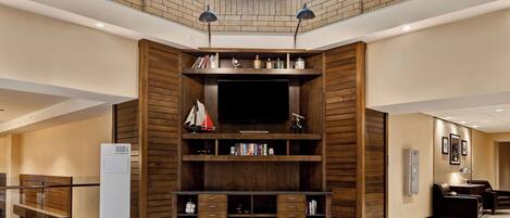 Una habitación amplia con mueble empotrado para entretenimiento, un televisor de pantalla plana y una estantería de madera.