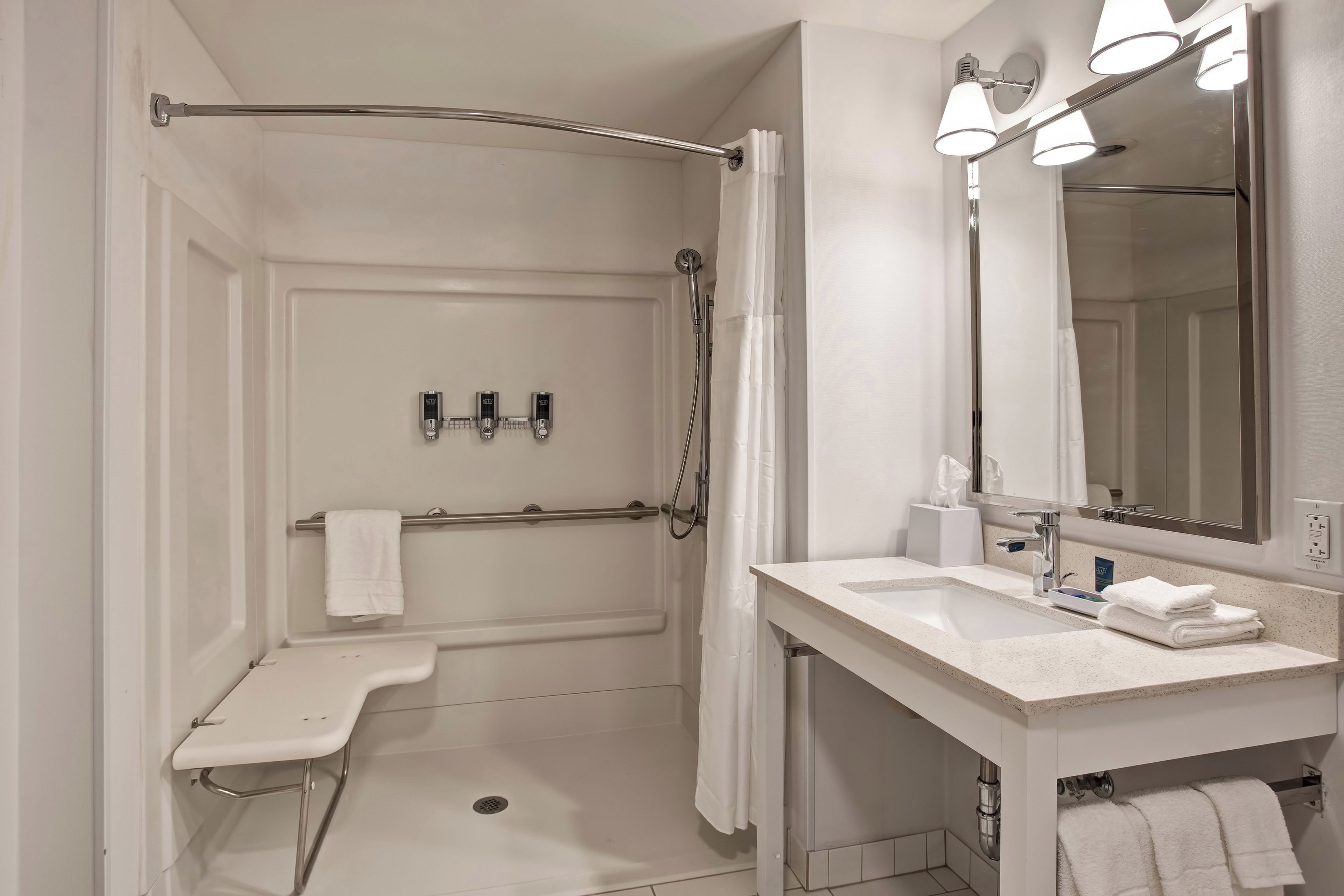 A modern bathroom with a walk-in shower, a vanity with a sink, and a mirror.