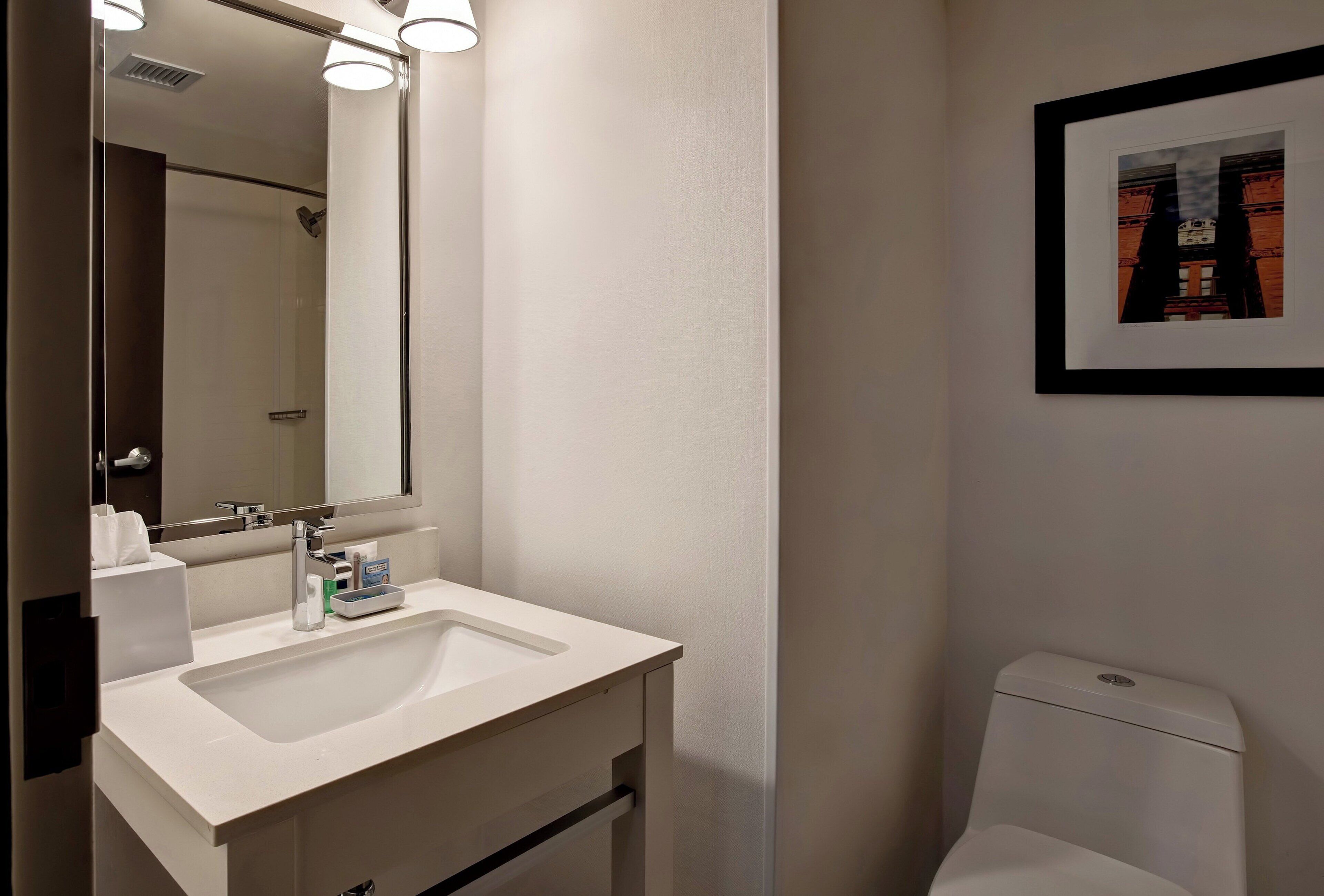 A bathroom with a white sink, mirror, and toilet.