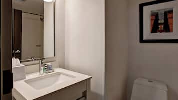 A bathroom with a white sink, mirror, and toilet.