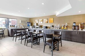 A modern kitchen area with a counter, seating, and various appliances.
