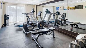 A gym with treadmills, elliptical machines, and weight benches.