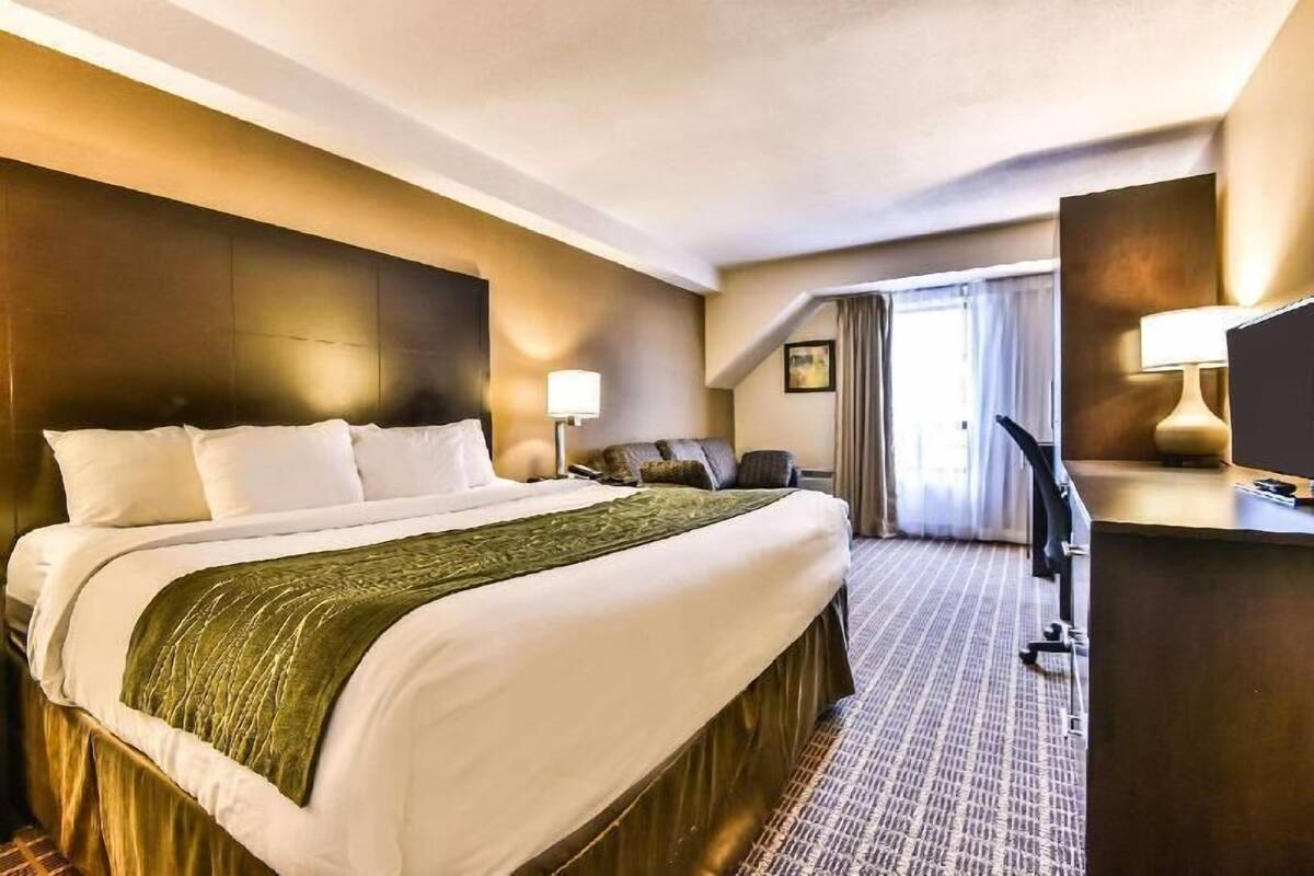 A hotel room with a large bed, a desk, and a chair.