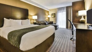 A hotel room with a large bed, a desk, a chair, and a TV.
