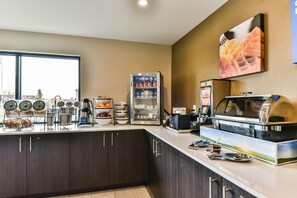 A breakfast bar with a refrigerator, coffee maker, and a food display.