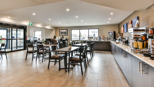 A modern cafe with tables and chairs, a counter with food items, and a view of the outside.